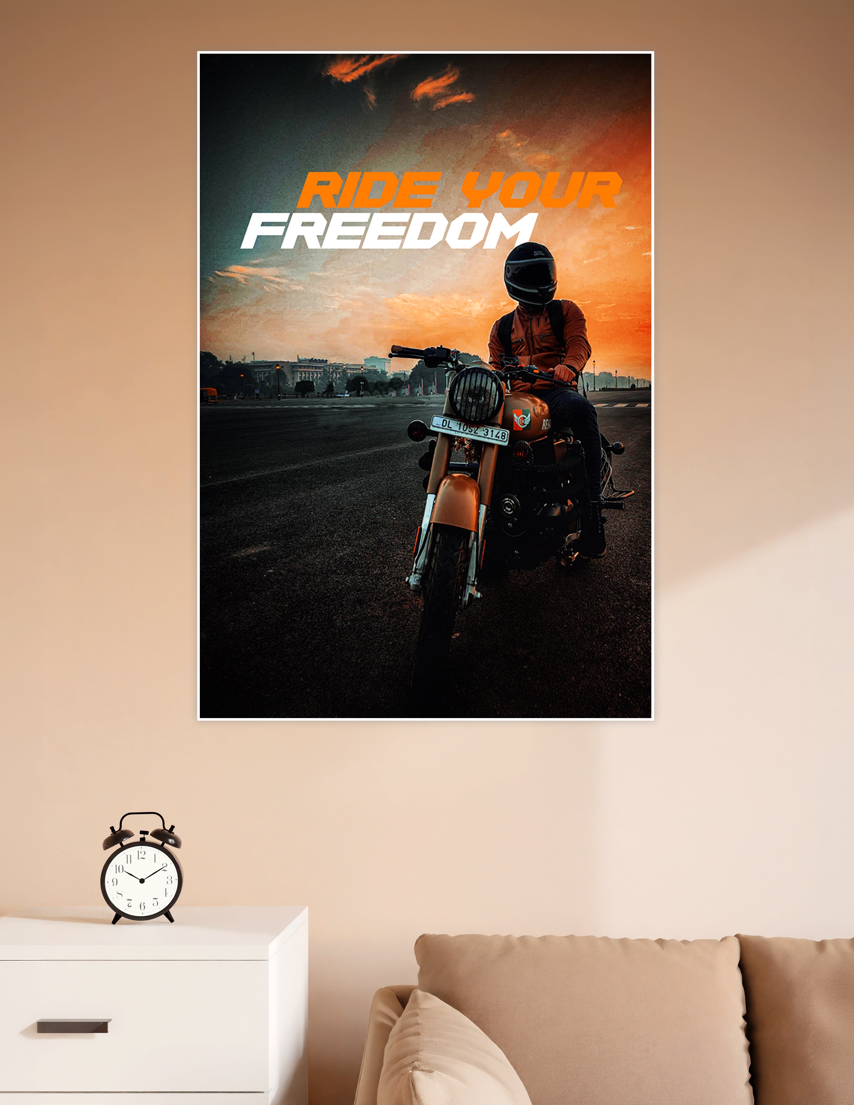 Helmeted motorcycle rider on a Royal Enfield against a dramatic orange sunset sky with bold 'Ride Your Freedom' typography poster