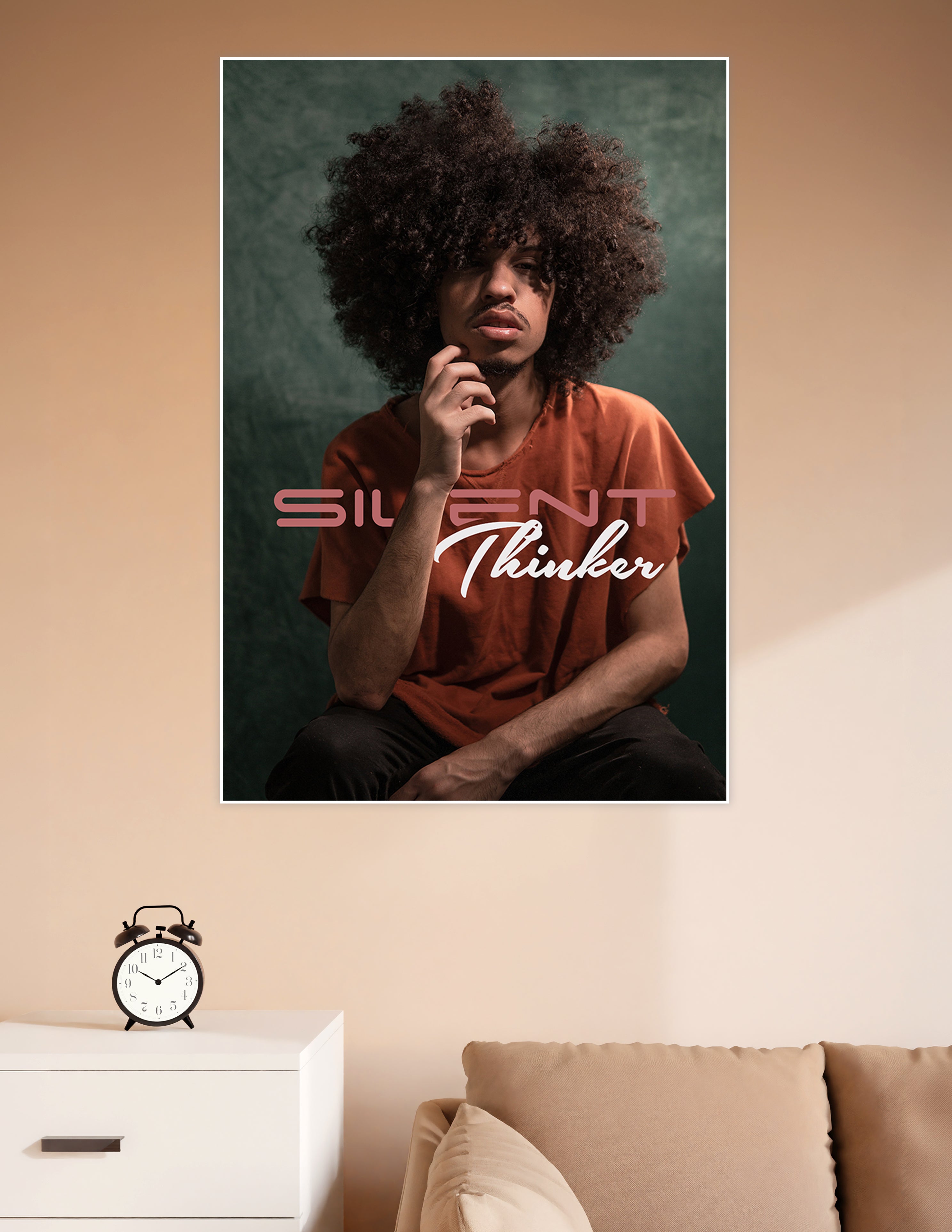 Studio portrait poster of a young man with a large afro in deep thought, wearing a rust-orange shirt against a teal background, with 'Silent Thinker' text overlay