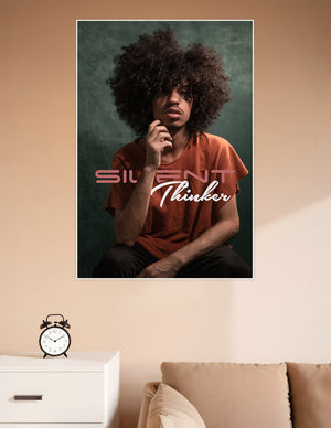 Studio portrait poster of a young man with a large afro in deep thought, wearing a rust-orange shirt against a teal background, with 'Silent Thinker' text overlay