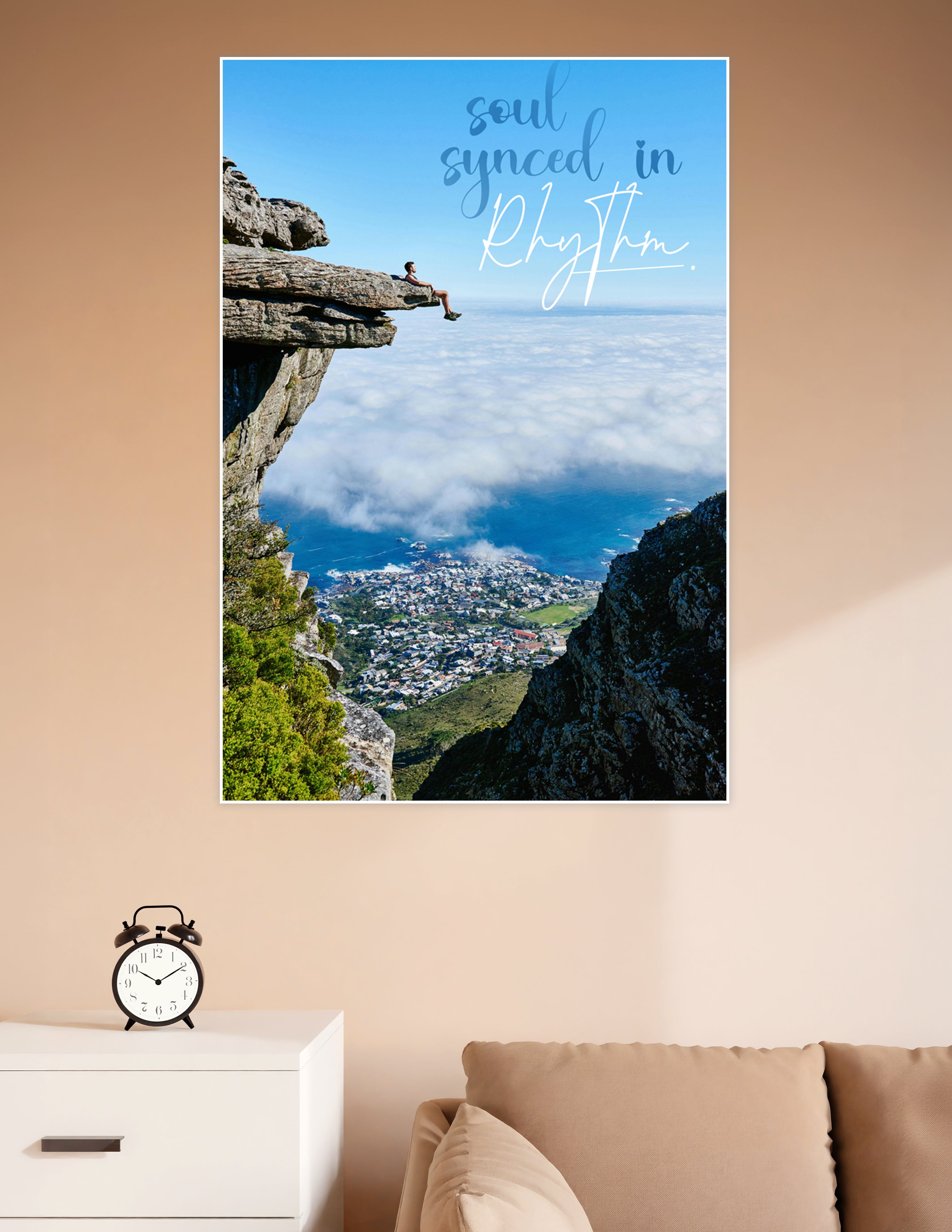 A person sitting on a rocky cliff edge high above clouds and a coastal city with the quote 'soul synced in rhythm' overlaid on a blue sky background