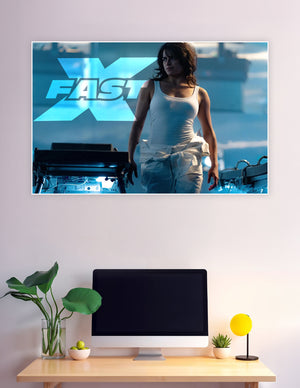 Fast X movie promotional poster featuring a fierce female action hero in a white tank top against a dramatic blue industrial background with the Fast X logo