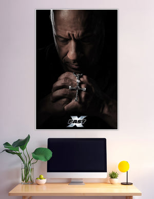 Fast X movie poster showing Dominic Toretto praying with hands clasped around a silver cross necklace against a dark dramatic background