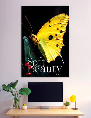 Close-up macro poster of a vivid yellow butterfly with red and black markings perched on a dark green leaf against a black background, titled Soft Beauty