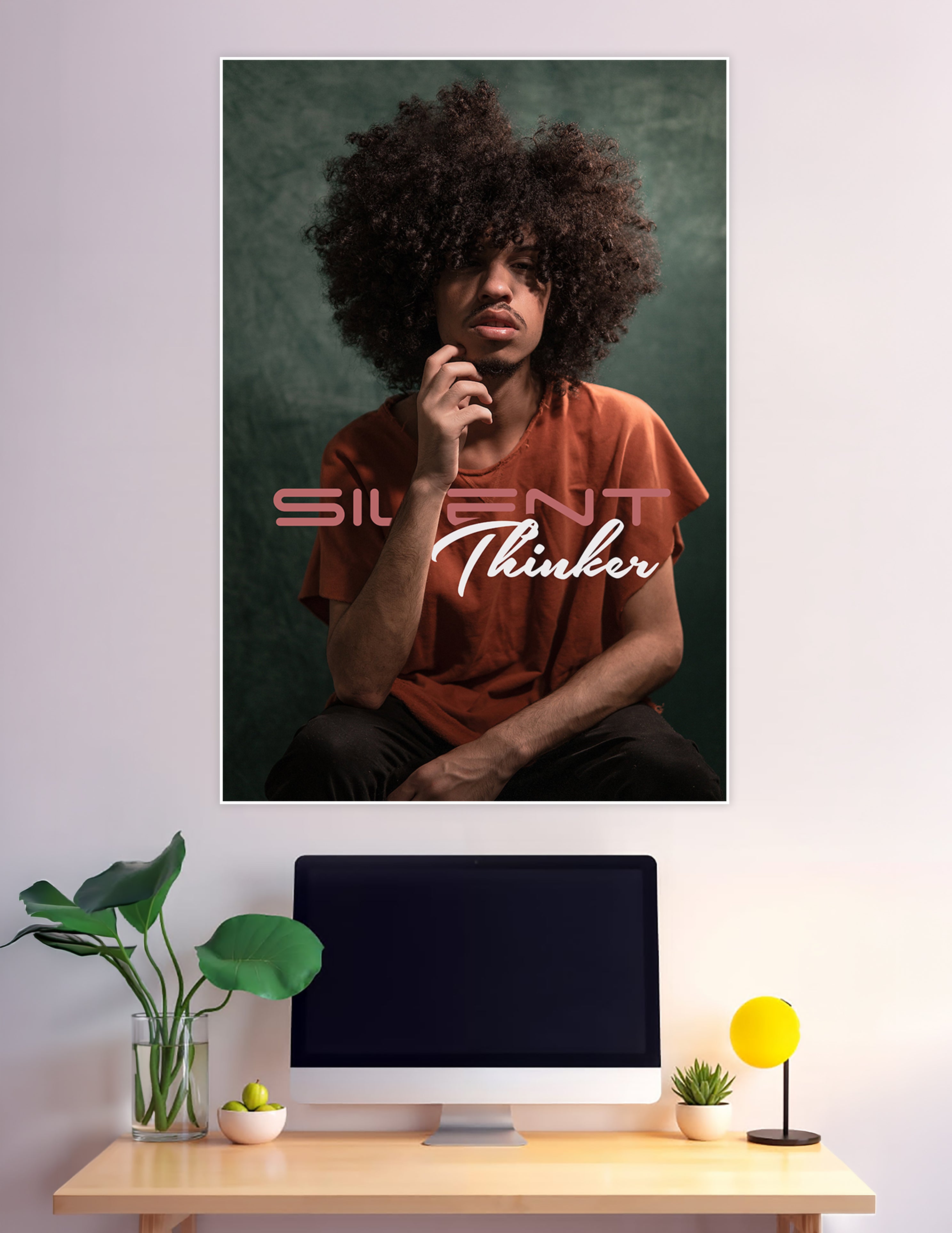 Studio portrait poster of a young man with a large afro in deep thought, wearing a rust-orange shirt against a teal background, with 'Silent Thinker' text overlay