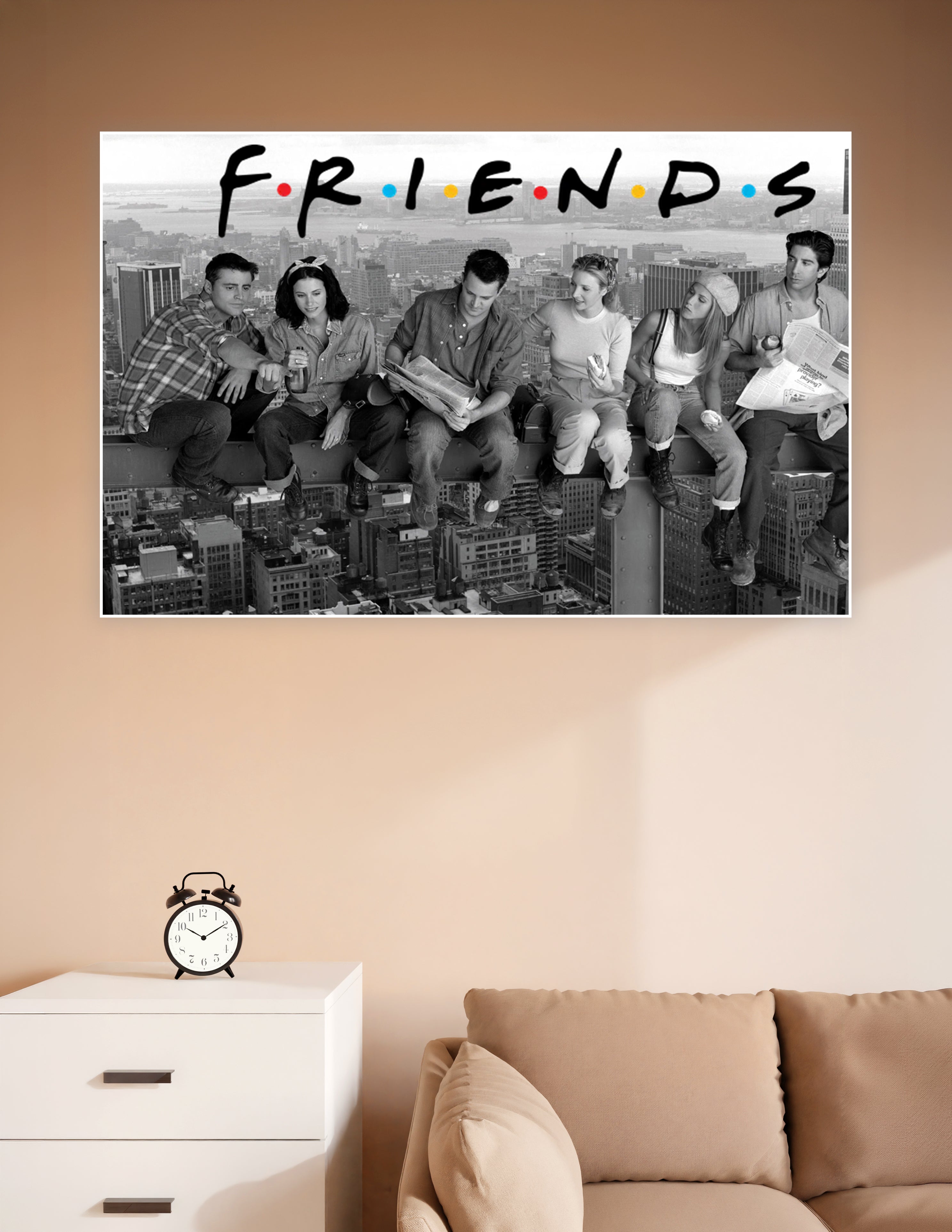 Black and white Friends TV show poster with cast sitting on a skyscraper beam above the New York City skyline with the colorful Friends logo at the top