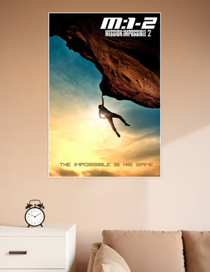 Mission Impossible 2 movie poster showing a silhouetted figure hanging from a rock overhang against a dramatic golden sunset sky with the tagline The Impossible Is His Game