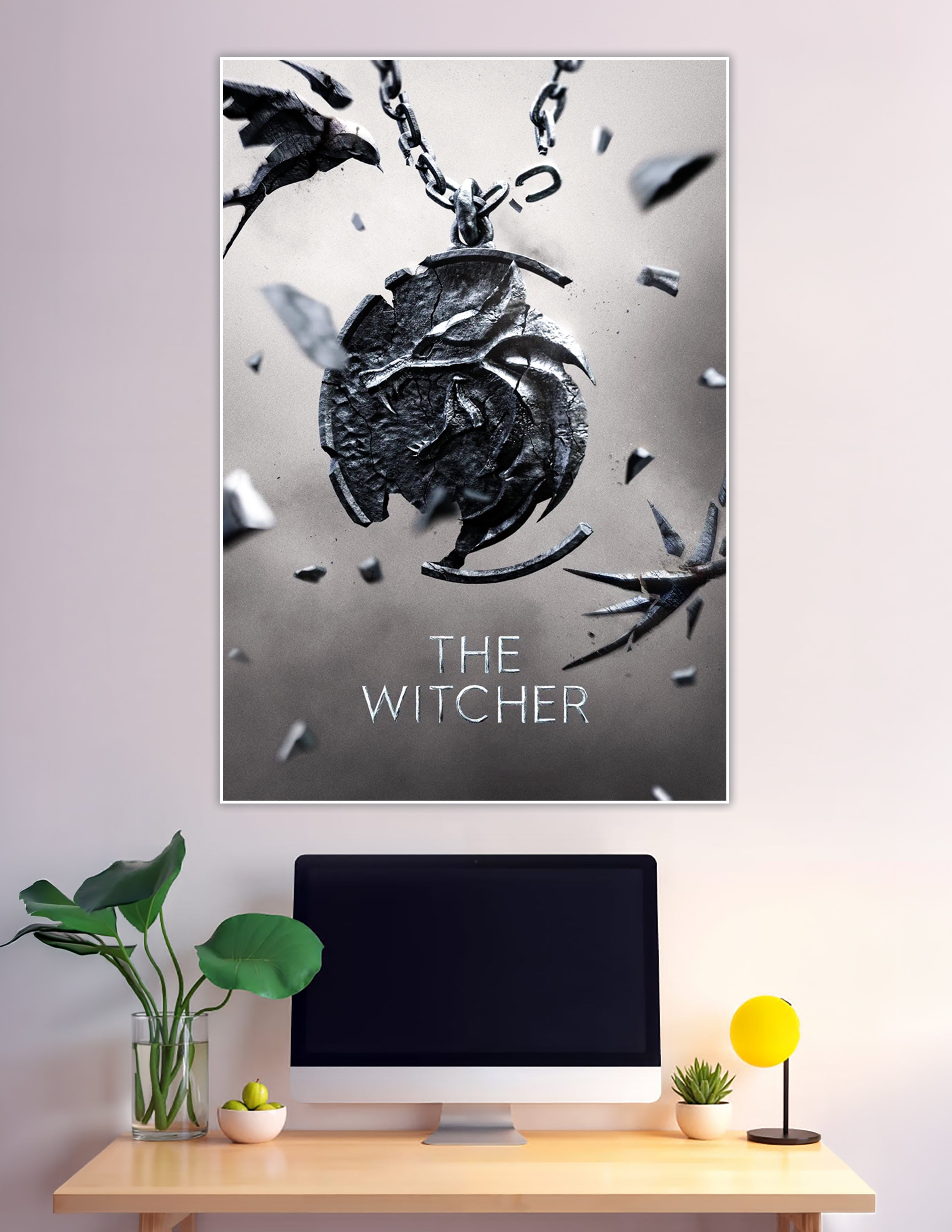 The Witcher official poster featuring the iconic Wolf Medallion shattering apart on a chain against a grey background with the title text below