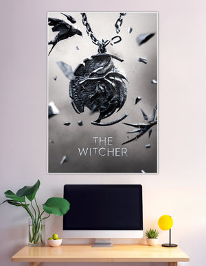 The Witcher official poster featuring the iconic Wolf Medallion shattering apart on a chain against a grey background with the title text below